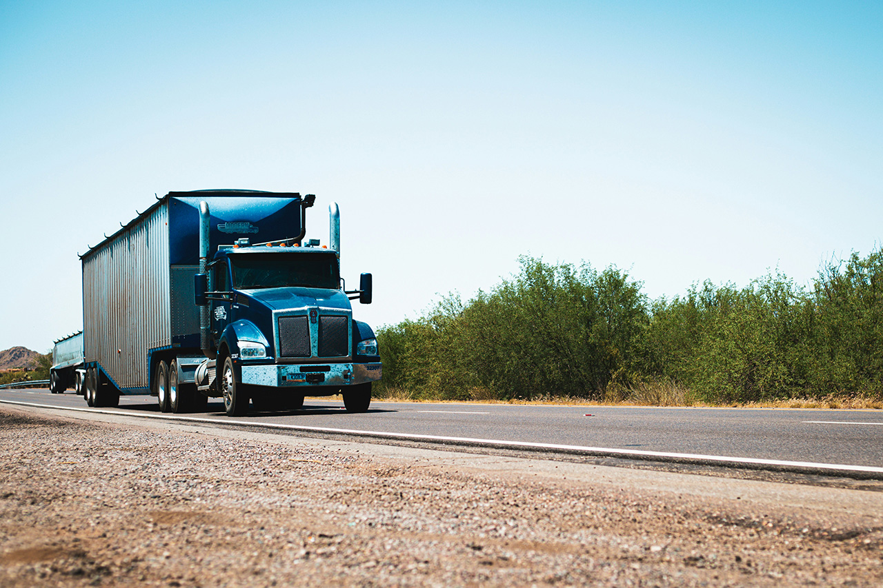 A blue semi truck driving through the desert.