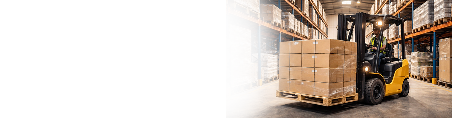 Photo of a forklift in a warehouse hauling a pallet
