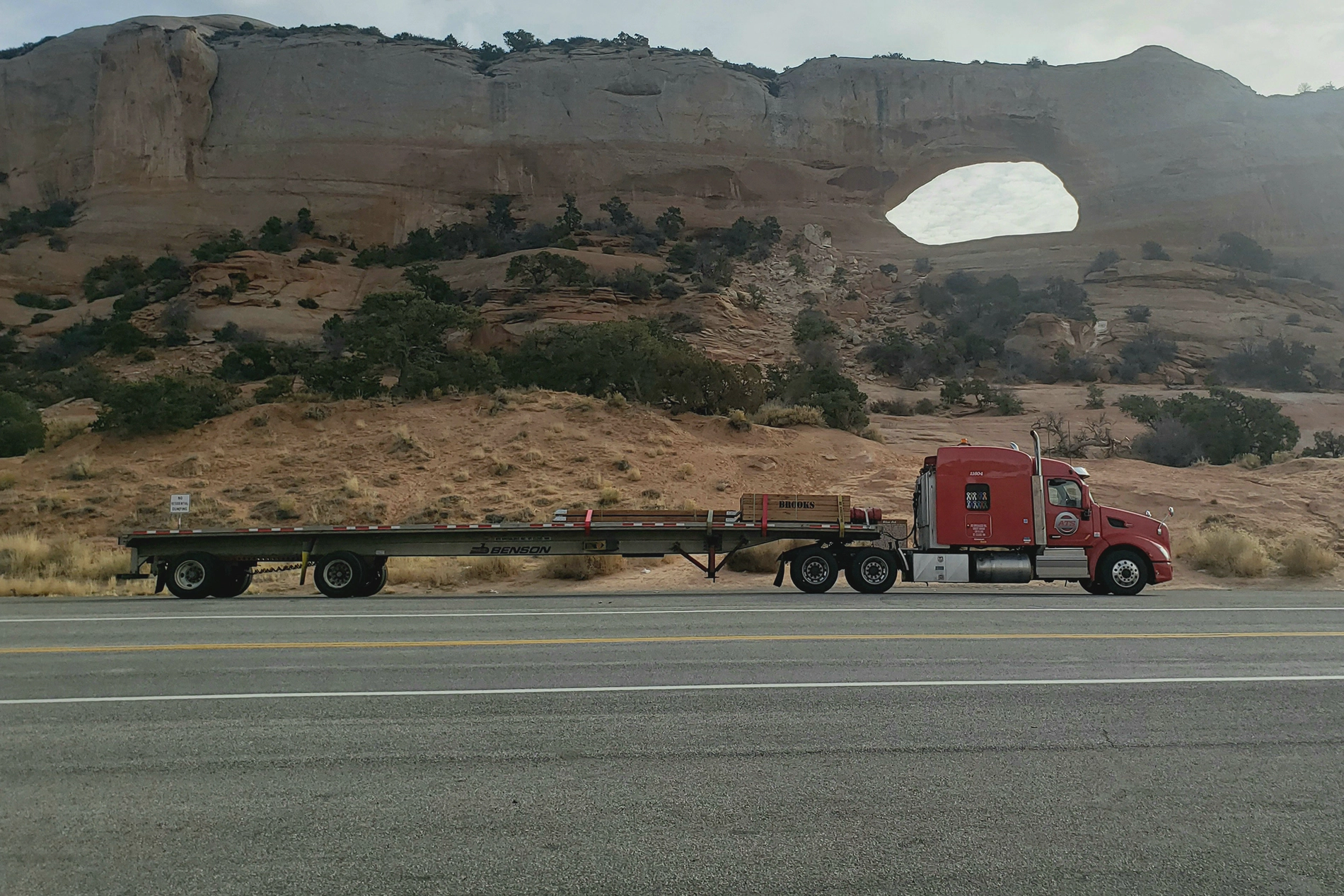 A photograph of a semi truck driving over a bridge.
