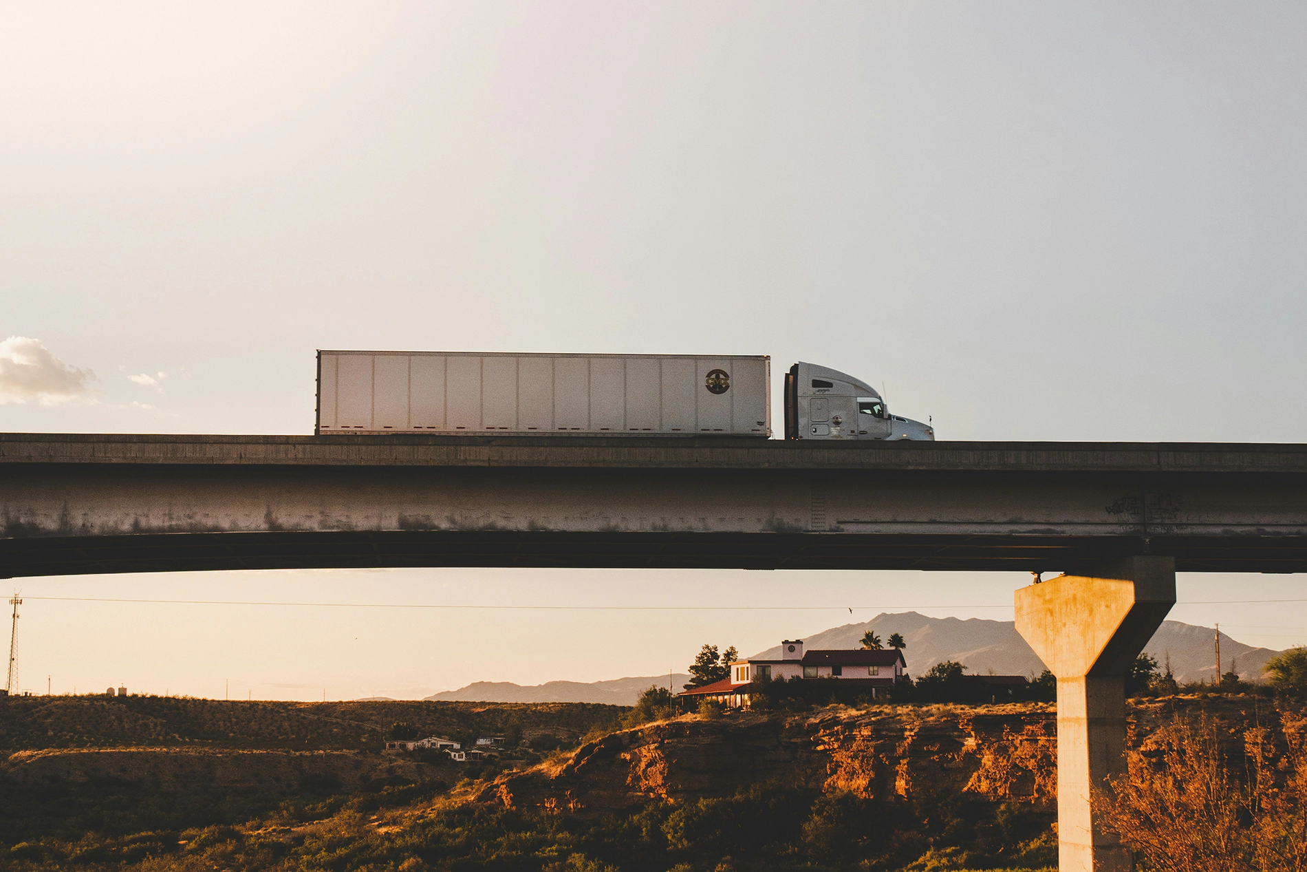 A photograph of a semi truck driving on a bridge.