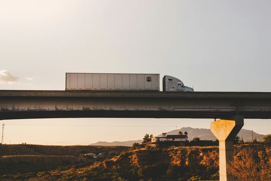 A photograph of a semi truck driving over a bridge. A photograph of a semi truck driving over a bridge.